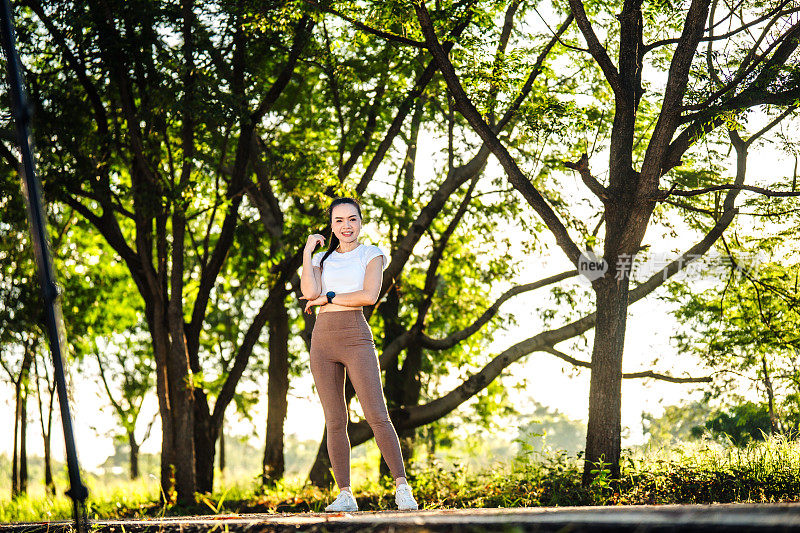 Fitness runner girl in public park,Young beautiful Asian woman in sports outfits doing stretching before workout outdoor in the park in the morning to get a healthy lifestyle. Healthy young woman warming up outdoors.
